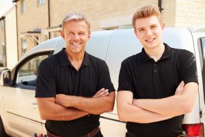 young-and-middle-aged-hvac-technicians-standing-in-front-of-van