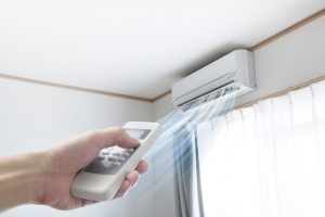 ductless-air-handler-in-background-with-hand-holding-remote-in-foreground