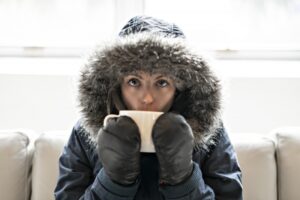 woman-inside-with-parka-on-drinking-out-of-mug